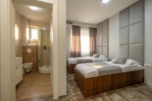ein Schlafzimmer mit 2 Betten und ein Badezimmer mit Dusche in der Unterkunft Motel Milošević in Bijeljina