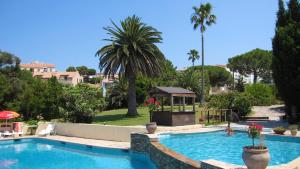 a swimming pool with a gazebo and palm trees at Hotel Bellevue in Saint-Florent