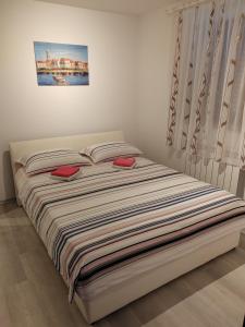 uma cama com duas almofadas vermelhas num quarto em Rooms Neda em Izola