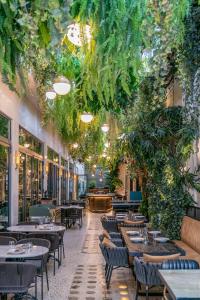 ein Restaurant mit Tischen, Stühlen und Pflanzen in der Unterkunft Gatsby Athens in Athen