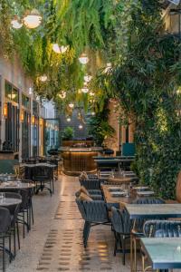 un restaurante con mesas, sillas y plantas en Gatsby Athens, en Atenas