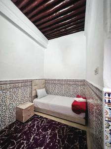 een kleine slaapkamer met een bed en een houten plafond bij Riad Yamna in Rabat
