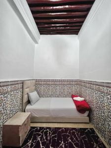 een bed in een kamer met een muur bij Riad Yamna in Rabat