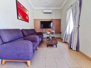 ein Wohnzimmer mit einem lila Sofa und einem TV in der Unterkunft Sg Rengit City Resort 1 in Kampung Sungai Rengit