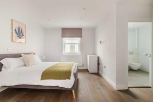 um quarto branco com uma cama e uma casa de banho em Modern House in South Kensington em Londres