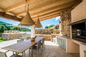 un patio con una mesa de madera y una pared de piedra en Finca Can Roig en Es Carritxo