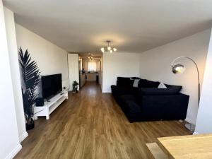 sala de estar con sofá negro y TV de pantalla plana en Pass the Keys 3 Bed home away from home en Colchester