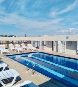 a pool on the roof of a building with lounge chairs at Flat em São Vicente in São Vicente