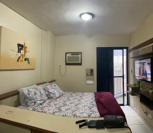 um quarto com uma cama e uma televisão em Flat em São Vicente em São Vicente
