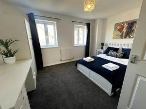 una camera con un letto blu e bianco e due finestre di Pass the Keys 3 Bed home away from home a Colchester