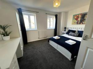 a bedroom with a blue and white bed and two windows at Pass the Keys 3 Bed home away from home in Colchester