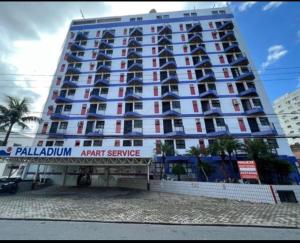 a large apartment building with a sign in front of it at Flat em São Vicente in São Vicente