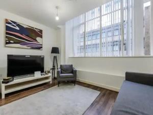 a living room with a flat screen tv and a chair at Pass the Keys Chic Strand Studio in Liverpool