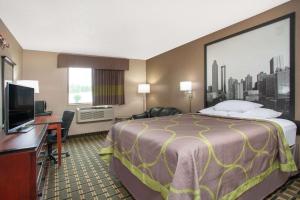 a hotel room with a bed and a flat screen tv at Super 8 by Wyndham Waycross GA in Waycross