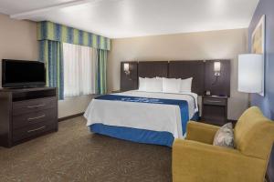 a hotel room with a bed and a television at Days Inn & Suites by Wyndham East Flagstaff in Flagstaff