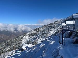 una montaña cubierta de nieve con un lodge de esquí. en Nivriti Stays, en Kanatal