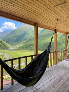 a hammock on a porch with a view of mountains at Shio's Stonehouse in Tusheti in Tusheti