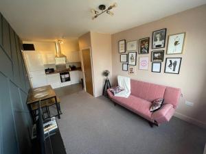 ein Wohnzimmer mit einem rosa Sofa und Bildern an der Wand in der Unterkunft Stylish 1-Bed Apartment in Swindon in Swindon