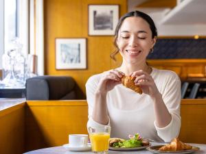 kobieta siedząca przy stole jedząca jedzenie w obiekcie Mercure Tokyo Ginza w Tokio