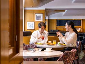 Ein Mann und eine Frau sitzen am Tisch und essen Essen. in der Unterkunft Mercure Tokyo Ginza in Tokio