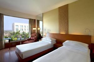 a hotel room with two beds and a large window at Hyatt Pune in Pune