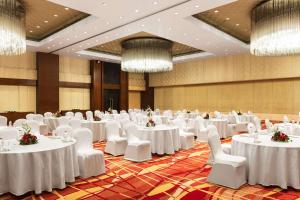 un salón de banquetes con mesas y sillas blancas y lámparas de araña en Hyatt Pune en Pune
