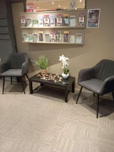 2 sillas y mesa de centro en la sala de espera en ibis les Etangs des Moines en Fourmies