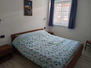 une chambre avec un lit avec une couette bleue et une fenêtre dans l'établissement Ciasa del Faure, à Pozza di Fassa