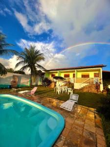 a house with a pool and a rainbow in the sky at Pousada Cruzeiro dos Anjos in Tabatinga