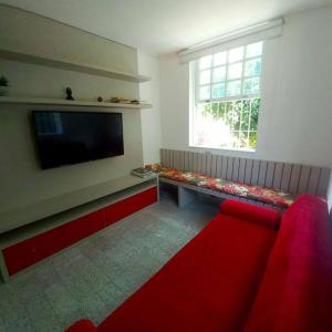 Il comprend un salon doté d'un canapé rouge et d'une télévision à écran plat. dans l'établissement Raridade! Mansão espetacular em Botafogo., à Rio de Janeiro