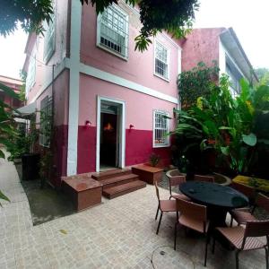 un bâtiment rose avec une table et des chaises devant lui dans l'établissement Raridade! Mansão espetacular em Botafogo., à Rio de Janeiro
