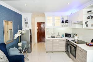 a kitchen with white cabinets and a glass table at Eirini Elegant - Rispetto Apartment with Power Backup in Midrand