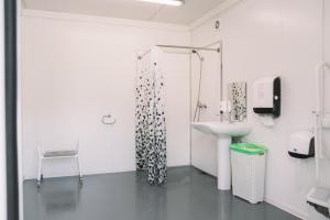 La salle de bains blanche est pourvue d'un lavabo et d'une douche. dans l'établissement Natur Camp Birštonas Small Cabins, à Birštonas