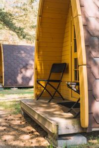 une chaise assise sur une terrasse couverte d'une maison jaune dans l'établissement Natur Camp Birštonas Small Cabins, à Birštonas