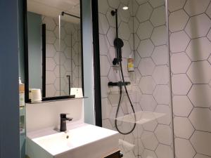a bathroom with a sink and a shower and a mirror at Greet Hôtel Orthez Bearn in Orthez