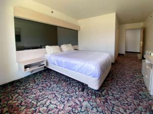 ein Hotelzimmer mit einem großen Bett und einem Schreibtisch in der Unterkunft Motel 6 McAlester OK - South in McAlester