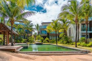 a pool with palm trees in front of a building at Stunning Belle Mare Beachfront luxury Apartment in Belle Mare