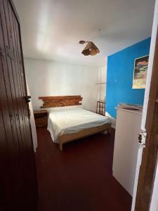 een kleine slaapkamer met een bed en een blauwe muur bij Casa Loquillo in Punta Hermosa
