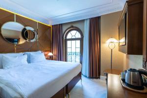 Wyndham Istanbul Old City في إسطنبول: غرفة نوم بسرير كبير ومرآة على الحائط