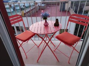 a pink table with two chairs and a vase of flowers on a balcony at Piso Vinaros in Vinarós