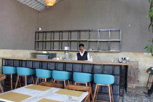 un homme debout derrière un bar dans un restaurant dans l'établissement Mango Leaf Lake Resort, à Pune