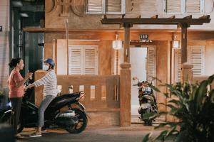 a woman riding a scooter with a woman standing on it at Thoai Mai House Phan Thiết in Ấp Bình Hưng