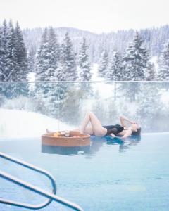 a woman laying in the water in a swimming pool at Elexus Apartments Poiana Brasov in Poiana Brasov