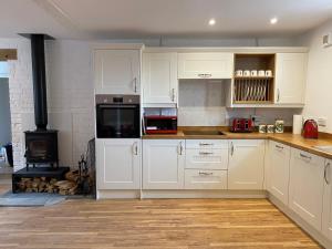 a kitchen with white cabinets and a stove at Monarchs View Farmstay in Michelmersh