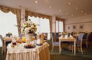 a dining room with tables and chairs and flowers at Hotel Ambiente Garni in Munich