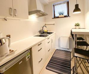 a small kitchen with white cabinets and a sink at Apartament CALMA & SPA in Kudowa-Zdrój