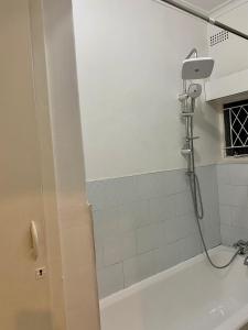 um chuveiro na casa de banho com uma parede de azulejos brancos em Remarkable 1-Bed Apartment in Kensington Harare 