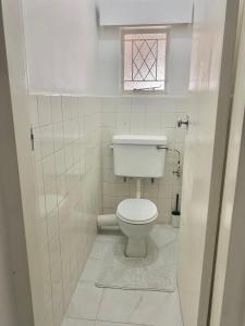uma casa de banho branca com um WC e uma janela em Remarkable 1-Bed Apartment in Kensington Harare 