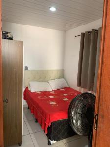 a small bedroom with a bed with a red blanket at Quarto e sala para carnaval in Salvador