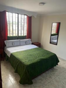 a bedroom with a large bed with a green blanket at Hotel Brisas Real in Bogotá